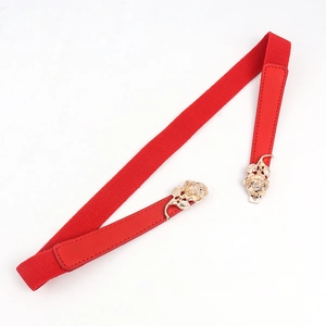 Détail d'une ceinture élastique rouge avec une boucle dorée en forme de rose élégante
