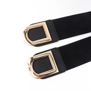 Detail of gold Double D buckle and black textured leather on women's elastic waist belt