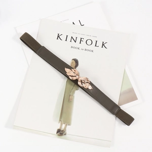 Slim olive green elastic belt for women featuring a gold leaf metal buckle on magazine