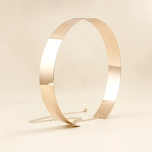 Macro detail of high-shine gold mirror metal waist belt with adjustable chain strap