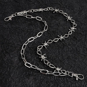 Detailweergave van de zilveren dubbele broekketting met prikkeldraad en sluitingen