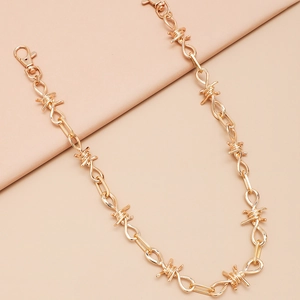 Detail van een gouden dubbellaagse punkketting met doornen en stevige karabijnsluitingen