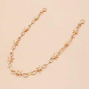 Detail van gouden punk broekketting met metalen doornschakels en karabijnsloten