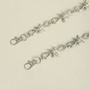 Detail van zilveren dubbellaagse hiphop-broekketting met punk doornendraad accenten