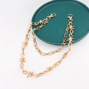 Detail van de gouden hiphopketting in doornstijl met karabijnsluitingen op groen bord