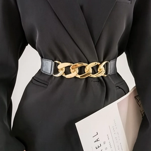 Women's black elastic waist belt with chunky gold chain buckle on a black blazer