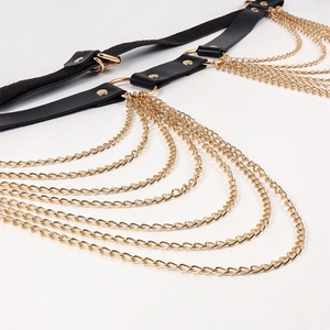 Detail of punk body chain featuring black leather straps, gold rivets and layered metal chains