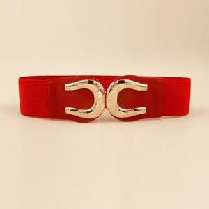Detailed macro view of the golden horseshoe buckle with embossed textures on red belt