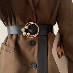 Elegant wide black leather belt with gold circular pearl buckle on brown blazer