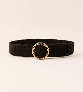 Detail of black woven belt with a gold round bamboo texture metal buckle for summer