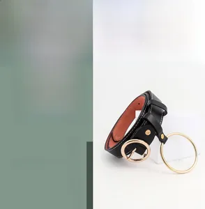 Détail d'une ceinture en cuir noir avec boucle ronde dorée et grand anneau en métal