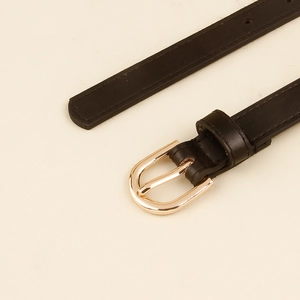 Detail eines minimalistischen schwarzen PU-Ledergürtels mit polierter hellgoldener D-Ring-Schnalle