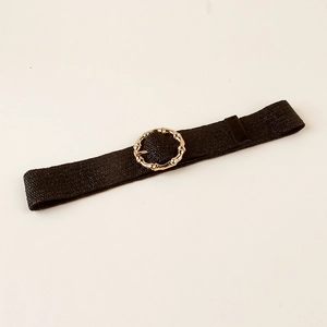 Detail of black elastic woven belt with a polished golden circular buckle on white surface