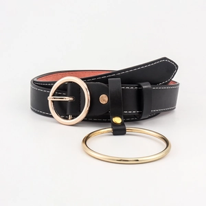 Détail de la ceinture en cuir noir avec boucle ronde dorée et anneau décoratif en métal