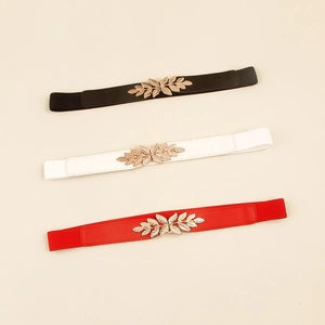 Détail de ceintures élastiques fines avec boucle en métal doré en forme de feuille ciselée