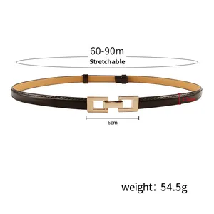 Detail view of a slim dark brown leather belt with a golden rectangular open buckle design