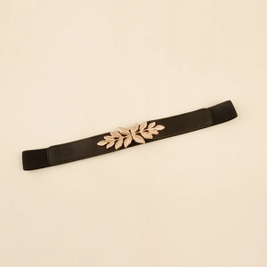 Détail d'une ceinture élastique noire avec une boucle dorée en forme de feuille de métal
