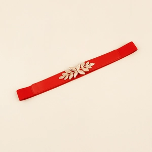 Détail de la ceinture élastique rouge avec boucle métallique dorée en forme de feuille