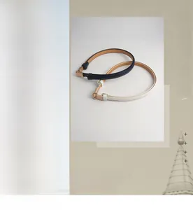 Detail of adjustable thin leather belts in black and white with gold metal buckles