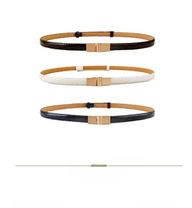 Close-up of three skinny belts in black, white, and navy blue with gold buckles