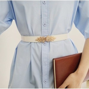 Ceinture élastique fine blanche pour femme avec boucle en métal dorée sur une robe bleue