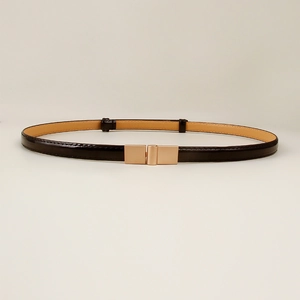 Detail of elegant black patent leather thin belt with rose gold metal buckle