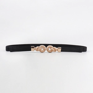 Close-up of thin elastic belt with a decorative golden metal double ring knot buckle