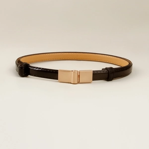 Detail view of thin black patent leather belt with a rectangular light gold metal buckle