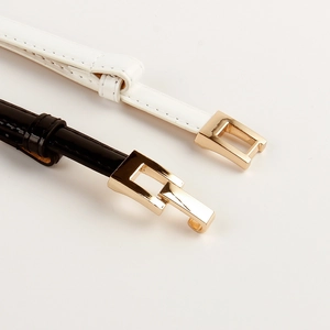 Detail of elegant black and white slim belts with geometric gold link buckles for dresses