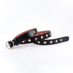 Slim black leather punk belt with gold round buckle and metallic eyelets on white background