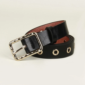 Black leather punk belt with gold metal eyelets and rectangular buckle on beige background