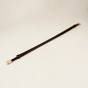 Detail of slim black faux leather belt with elegant golden metal hook hardware buckle