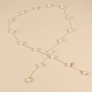 Détail d'une chaîne de corps dorée élégante avec perles blanches et petit fermoir