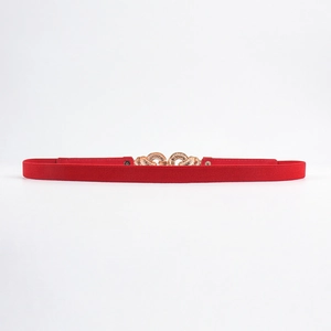 Detail of red elastic waist belt featuring a gold floral texture buckle for women