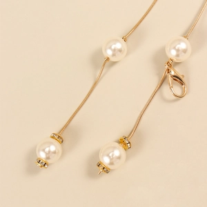 Détail de la ceinture chaîne dorée élégante avec perles blanches et fermoir mousqueton