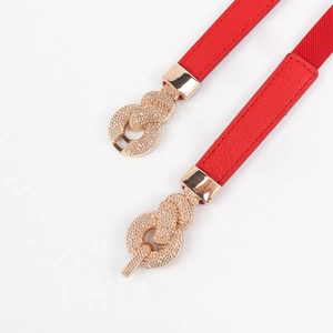 Detail of red elastic waist belt with textured light gold metal twist knot buckle