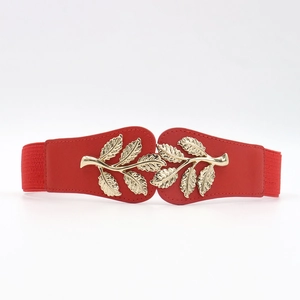 Close-up of golden leaf metal buckle and red elastic stretch belt for women