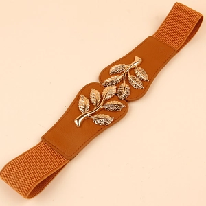 Detail of leaf-shaped gold metal buckle on brown elastic waist belt for women's dresses