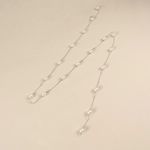 Détail de perles blanches élégantes sur une fine chaîne en métal argenté pour robes