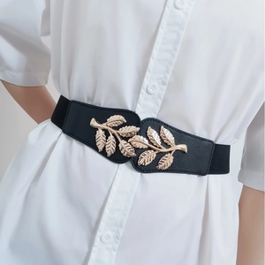 Elastic wide belt for women with golden leaf metal buckle on a white dress