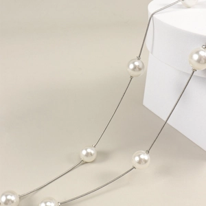 Vue macro de perles blanches faites à la main et chaîne serpent argentée pour robes