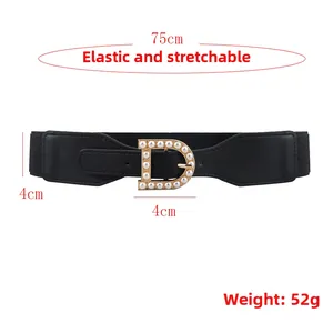 Close-up of black elastic belt with gold D-buckle and elegant white pearl inlay