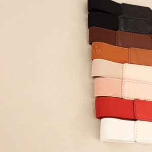Close-up of elastic waist belts in various colors featuring leather-textured closures