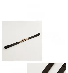 Close-up of a slim black elastic belt featuring a textured gold interlocking metal buckle