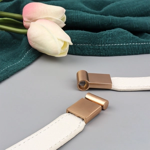 Close-up of white leather waist belt with matte gold square buckle and elastic detail