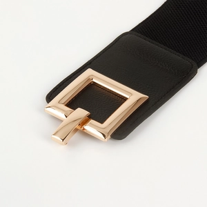 Close-up of a wide elastic waist belt with a large square gold metal buckle for women