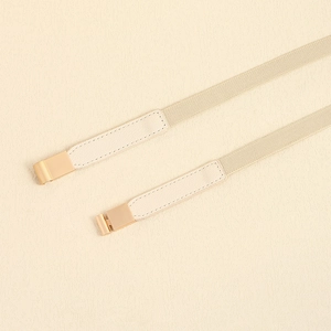 Detailed close-up of beige elastic waist belt with gold metal buckle and leather ends