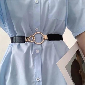 Detail of a black elastic waist belt with a golden double ring buckle on a light blue dress