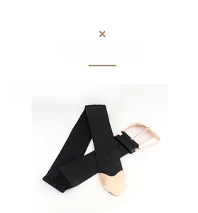 Detail of black elastic wide waist belt featuring gold buckle and heart-shaped metal tip