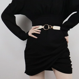 Detail of a thin beige leather belt with a round gold buckle on a black dress